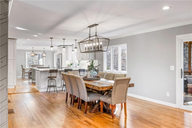 dining space featuring an inviting chandelier, light wood-style flooring, baseboards, and ornamental molding