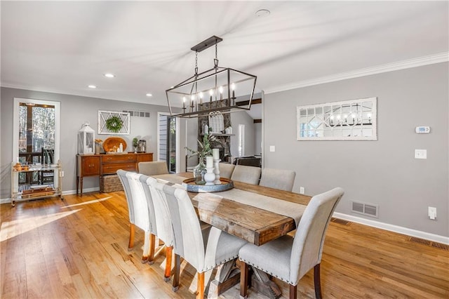 dining space with visible vents, an inviting chandelier, crown molding, light wood finished floors, and baseboards