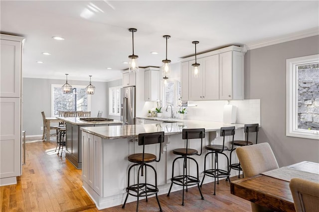 kitchen with backsplash, high end fridge, a peninsula, and light wood finished floors