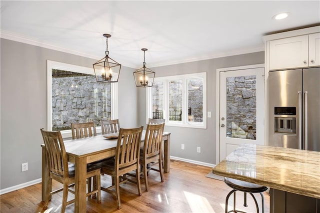 dining area with a notable chandelier, baseboards, light wood-style floors, and ornamental molding