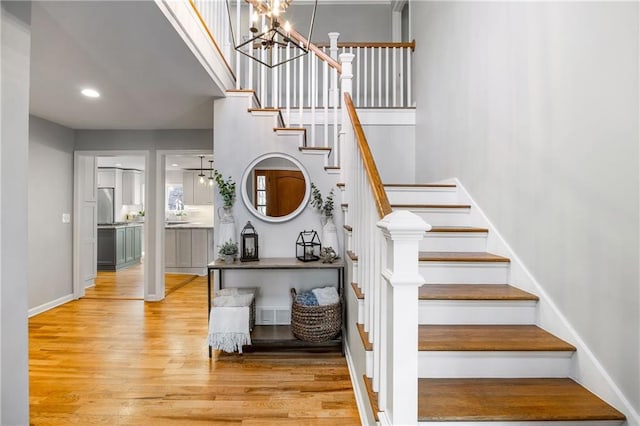 staircase with wood finished floors, baseboards, visible vents, an inviting chandelier, and recessed lighting