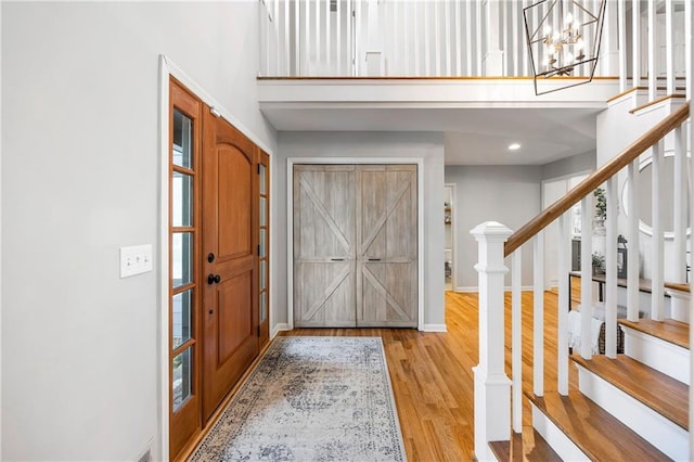 entryway with wood finished floors, stairway, a high ceiling, baseboards, and a chandelier