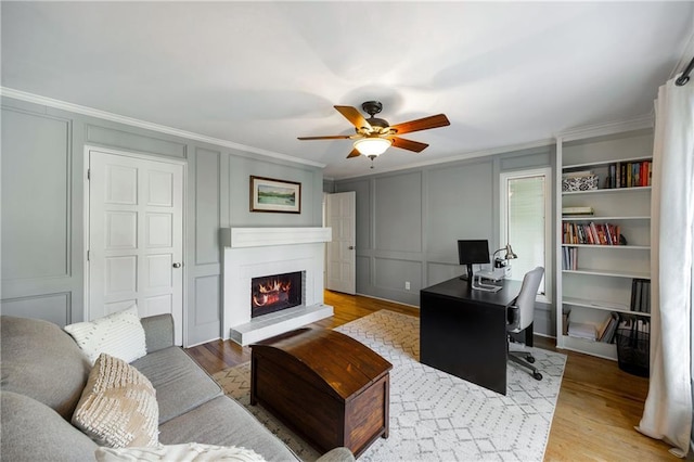 office featuring crown molding, wood finished floors, a ceiling fan, and a decorative wall