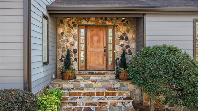 property entrance featuring stone siding and a shingled roof