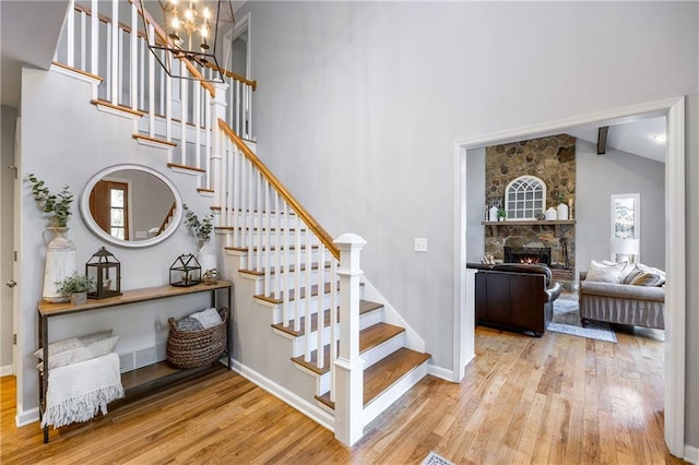 staircase featuring baseboards, high vaulted ceiling, and wood finished floors