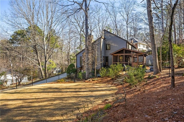 rear view of house featuring a yard, fence, a sunroom, and a chimney