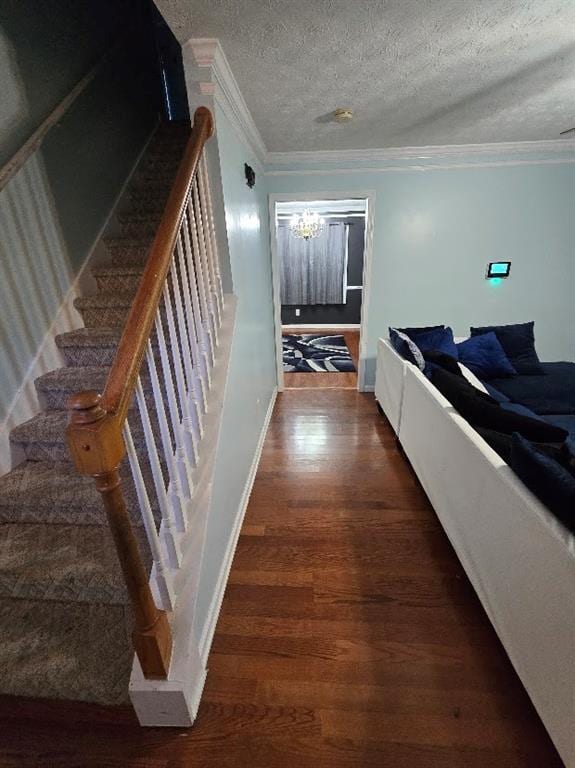 hallway with dark hardwood / wood-style floors, ornamental molding, a textured ceiling, and a chandelier