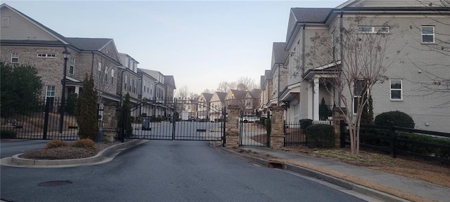 view of road with a residential view, a gate, a gated entry, and curbs