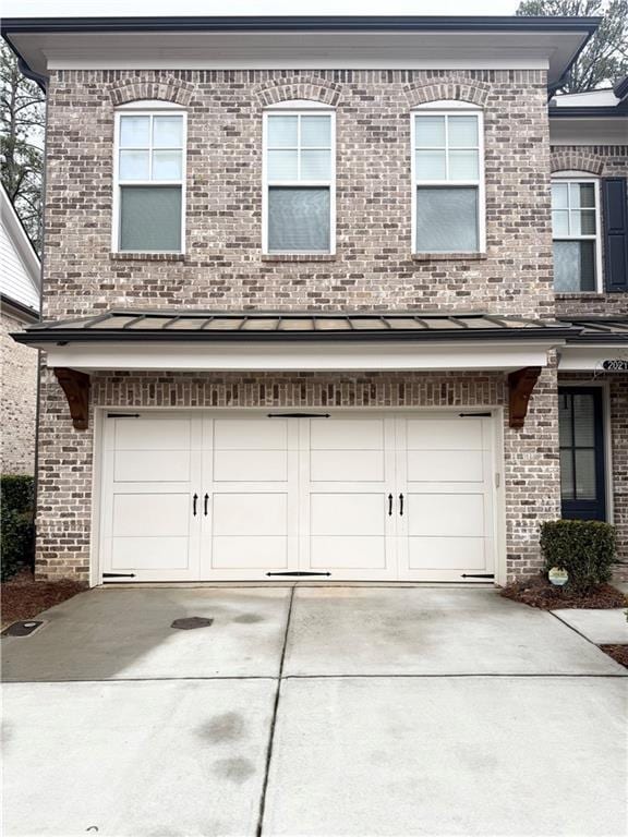 townhome / multi-family property featuring an attached garage, a standing seam roof, metal roof, and concrete driveway