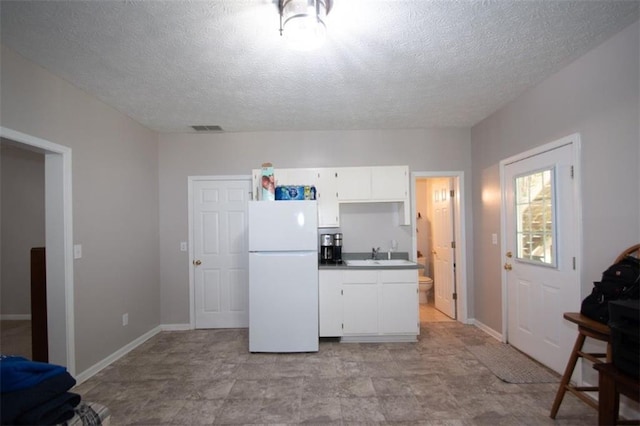 10 Stagg Trce, Social Circle, GA 30025 - kitchen with freestanding refrigerator, a sink, a textured ceiling, white cabinetry, and baseboards