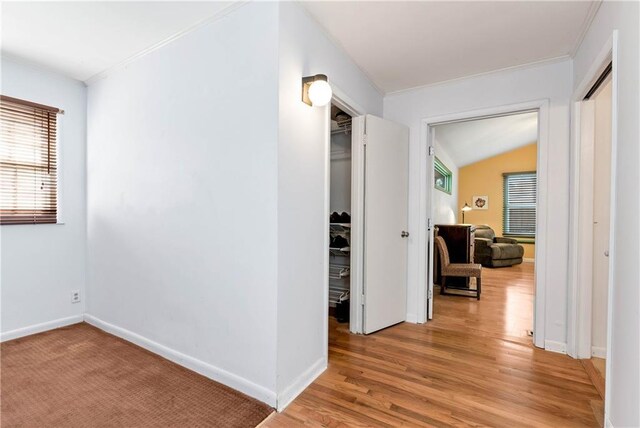 corridor with light hardwood / wood-style floors and lofted ceiling