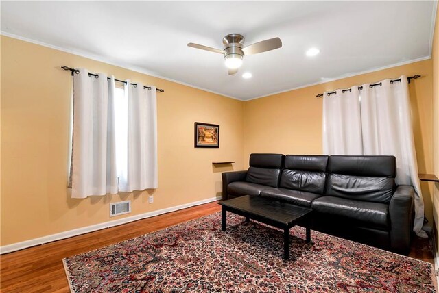 living room with wood-type flooring, ceiling fan, and crown molding