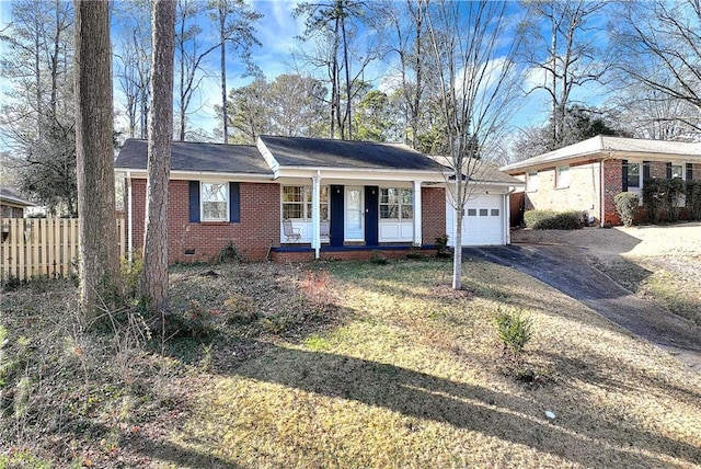 ranch-style house featuring a garage, covered porch, and a front lawn