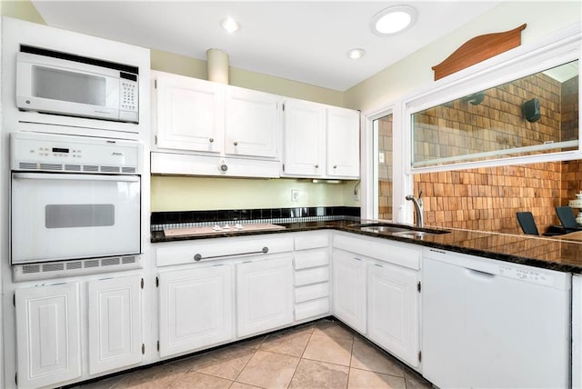 kitchen featuring sink, white cabinets, dark stone counters, light tile patterned floors, and white appliances