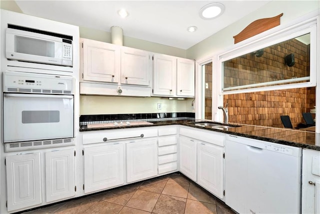 kitchen with white appliances, white cabinetry, light tile patterned floors, sink, and dark stone counters