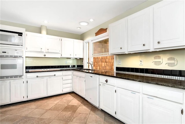 kitchen with white cabinetry, light tile patterned flooring, white appliances, and dark stone countertops