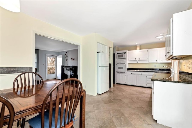 kitchen with sink, white appliances, white cabinets, and dark stone countertops