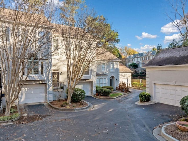 view of front of house featuring an attached garage, a residential view, aphalt driveway, and stucco siding