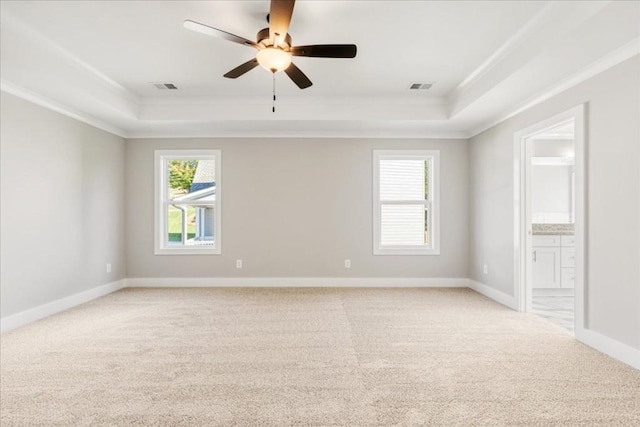 spare room featuring a tray ceiling, ceiling fan, and light colored carpet