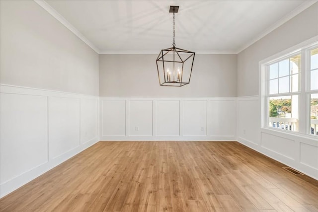 unfurnished dining area featuring crown molding, plenty of natural light, light hardwood / wood-style flooring, and an inviting chandelier