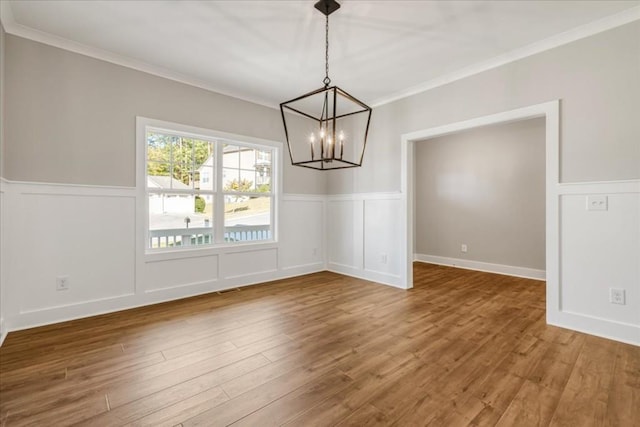 unfurnished dining area with a notable chandelier, wood-type flooring, and crown molding