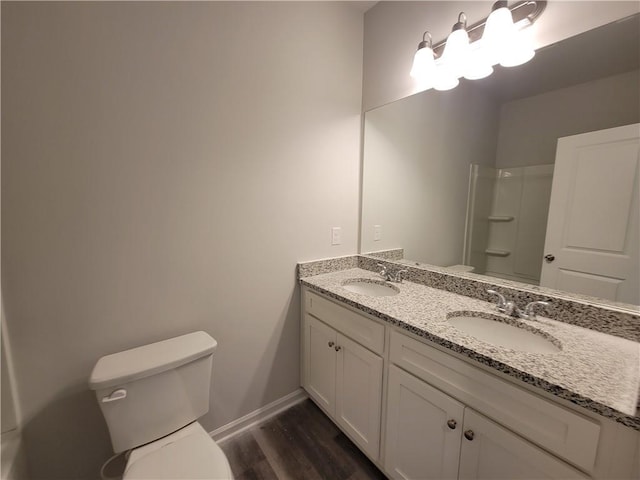 bathroom featuring toilet, hardwood / wood-style floors, walk in shower, and vanity