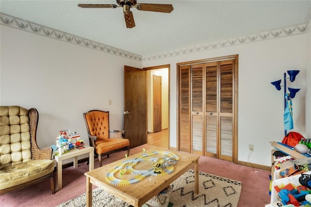 living area with ceiling fan, carpet floors, and a textured ceiling