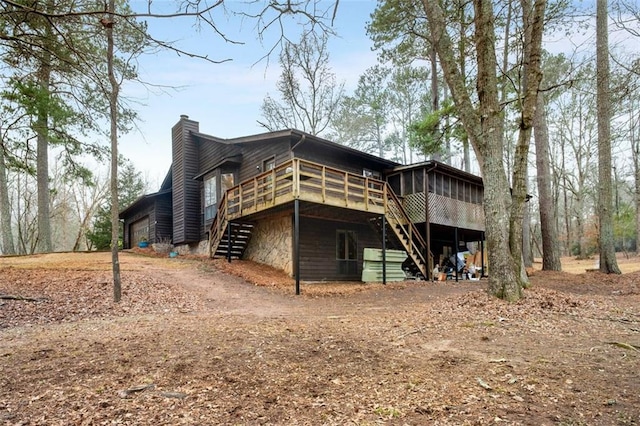 rear view of property featuring a garage, a deck, and a sunroom