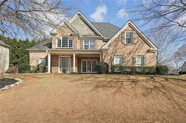 craftsman inspired home with roof with shingles, a front lawn, and brick siding