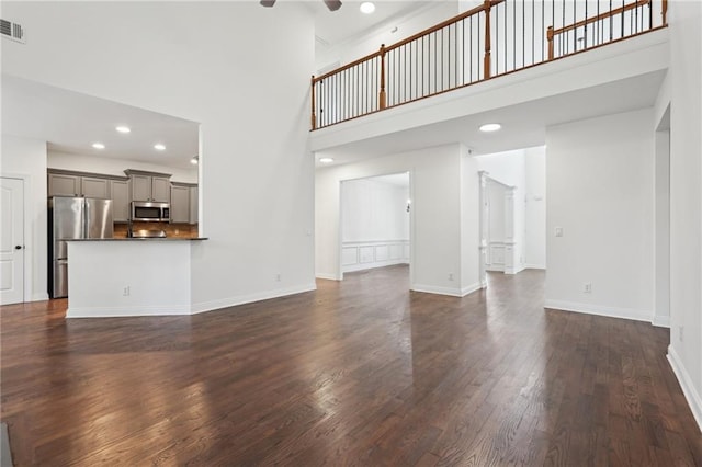 unfurnished living room featuring recessed lighting, a high ceiling, dark wood-type flooring, a ceiling fan, and baseboards