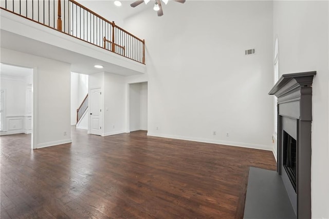 unfurnished living room featuring baseboards, a fireplace, visible vents, and dark wood-style flooring