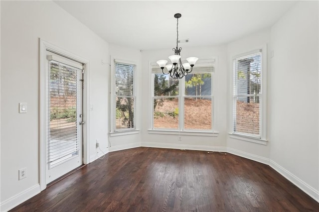 unfurnished dining area with dark wood-style floors, baseboards, visible vents, and an inviting chandelier