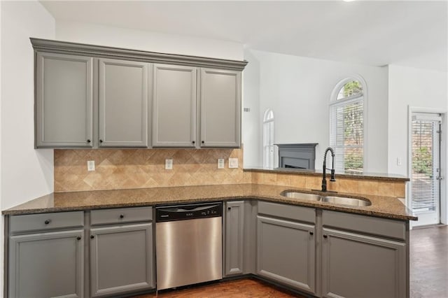 kitchen featuring dishwasher, a peninsula, gray cabinets, and a sink