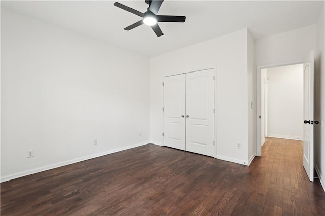 unfurnished bedroom featuring ceiling fan, a closet, baseboards, and dark wood-style flooring