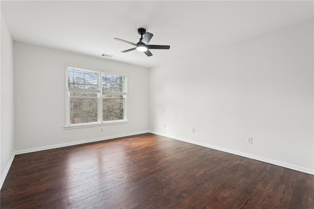 spare room with dark wood-style floors, visible vents, baseboards, and a ceiling fan