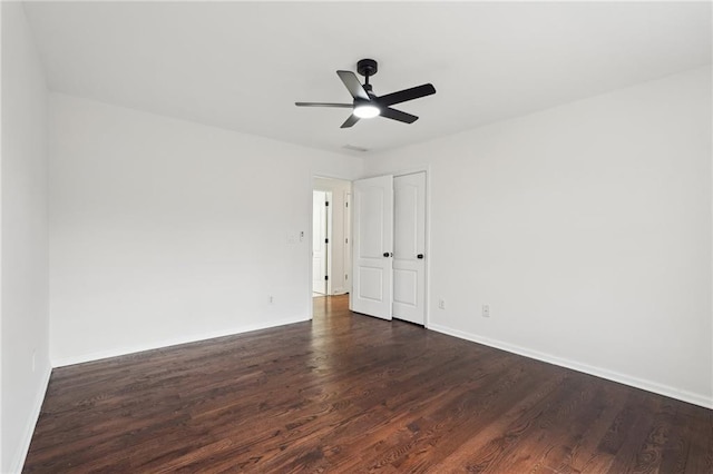 unfurnished room with dark wood-type flooring, ceiling fan, and baseboards