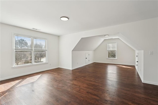 additional living space featuring vaulted ceiling, dark wood-style flooring, visible vents, and baseboards