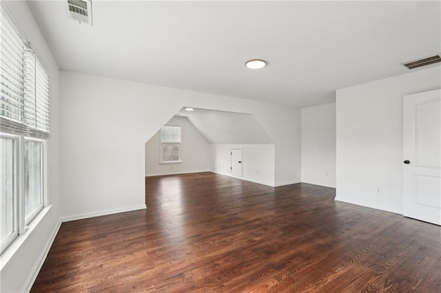 bonus room with visible vents, vaulted ceiling, and dark wood-type flooring