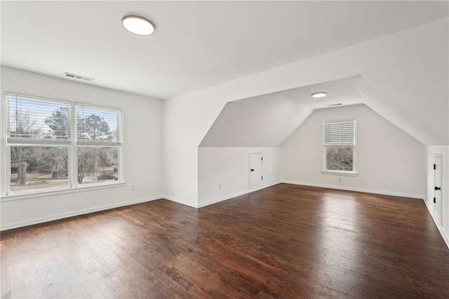 bonus room with vaulted ceiling, dark wood finished floors, visible vents, and baseboards