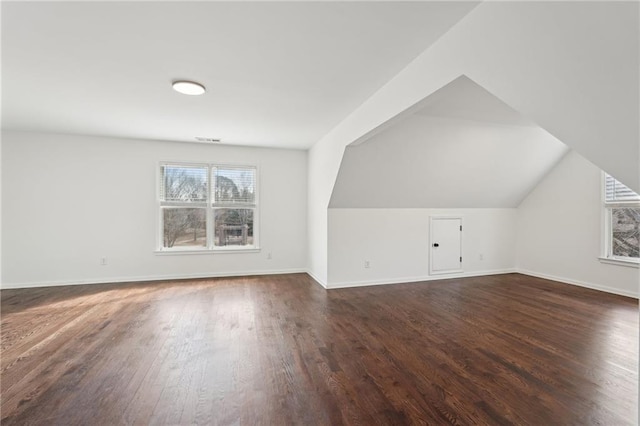 additional living space featuring vaulted ceiling, visible vents, dark wood finished floors, and a wealth of natural light