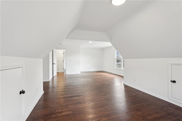 additional living space featuring lofted ceiling, baseboards, and dark wood-style flooring