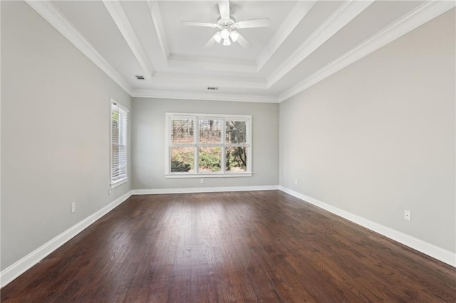 empty room with ornamental molding, dark wood-style flooring, a raised ceiling, and baseboards