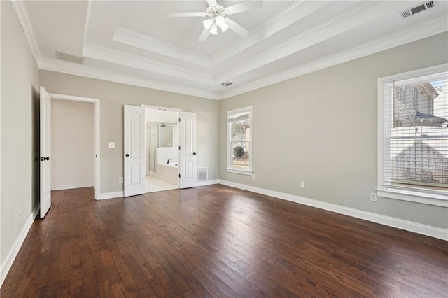 unfurnished bedroom featuring a tray ceiling, dark wood-type flooring, multiple windows, and visible vents