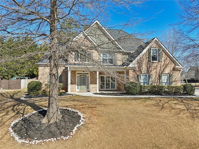 view of front of house featuring brick siding, a front yard, and fence