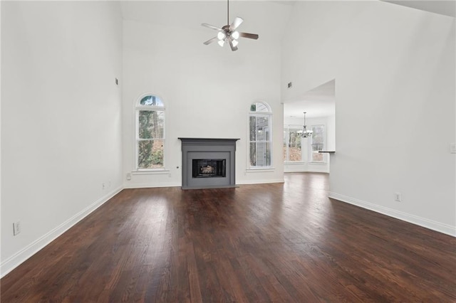 unfurnished living room with a fireplace with flush hearth, baseboards, dark wood-style flooring, and ceiling fan with notable chandelier