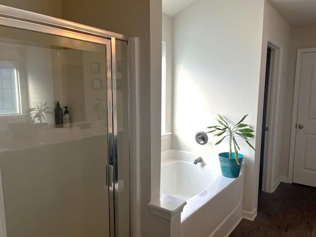 bathroom featuring a garden tub, wood finished floors, and a shower stall