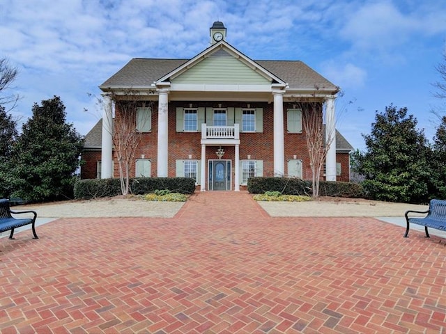 greek revival house featuring brick siding and a balcony