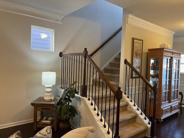 staircase with ornamental molding, wood finished floors, and baseboards