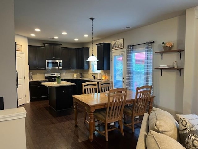 kitchen featuring dark wood finished floors, a kitchen island, appliances with stainless steel finishes, light countertops, and recessed lighting