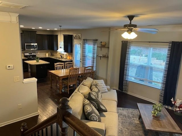 living room with ceiling fan, dark wood-style flooring, visible vents, and baseboards